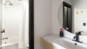 Une salle de bain moderne avec une baignoire blanche, un grand miroir et un lavabo doté d’un robinet noir.