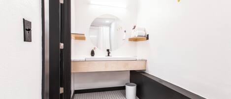 A modern bathroom with a white sink, mirror, and hexagonal tile floor.