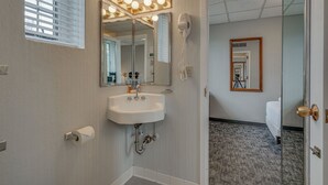 A bathroom with a sink, mirror, vanity lights, and a hairdryer.