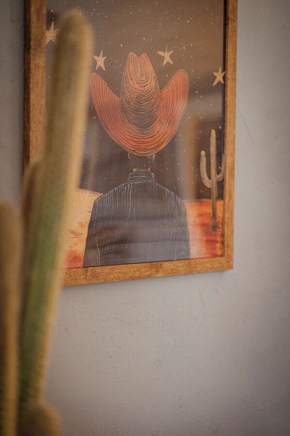 Una obra de arte enmarco que muestra a un vaquero con un sombrero grande, estrellas y un cactus.