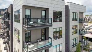 A modern multi-story building with balconies, large windows, and a rooftop pool area. - Omnia - Modern Luxe unit at The Odyssey! (Nashville)