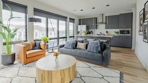 A modern living room with a grey sofa, a wooden coffee table, and a large window. - Omnia - Modern Luxe unit at The Odyssey! (Nashville)