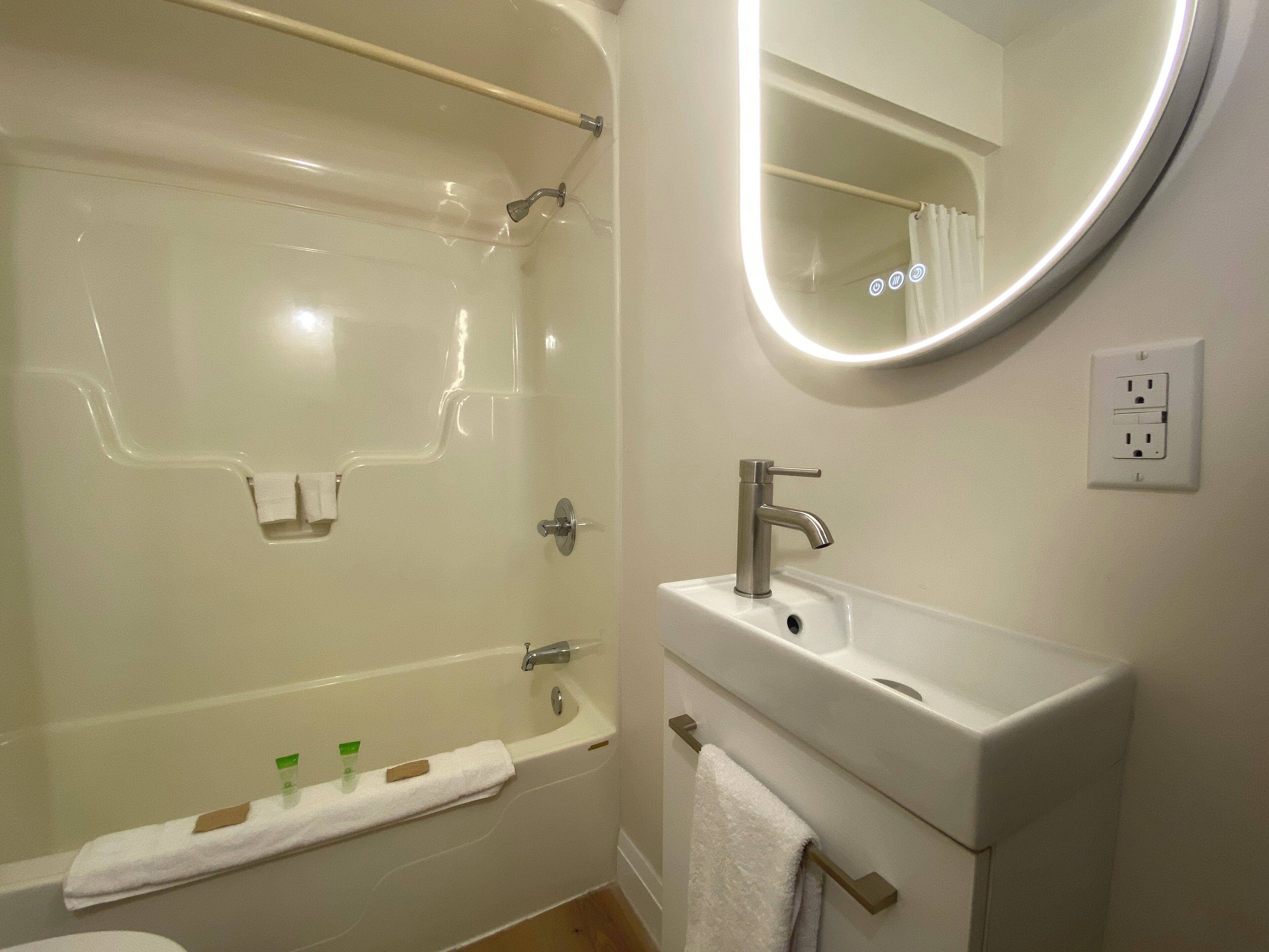 Une salle de bain équipée d’une baignoire, d’un lavabo, d’un miroir et d’un porte-serviettes.