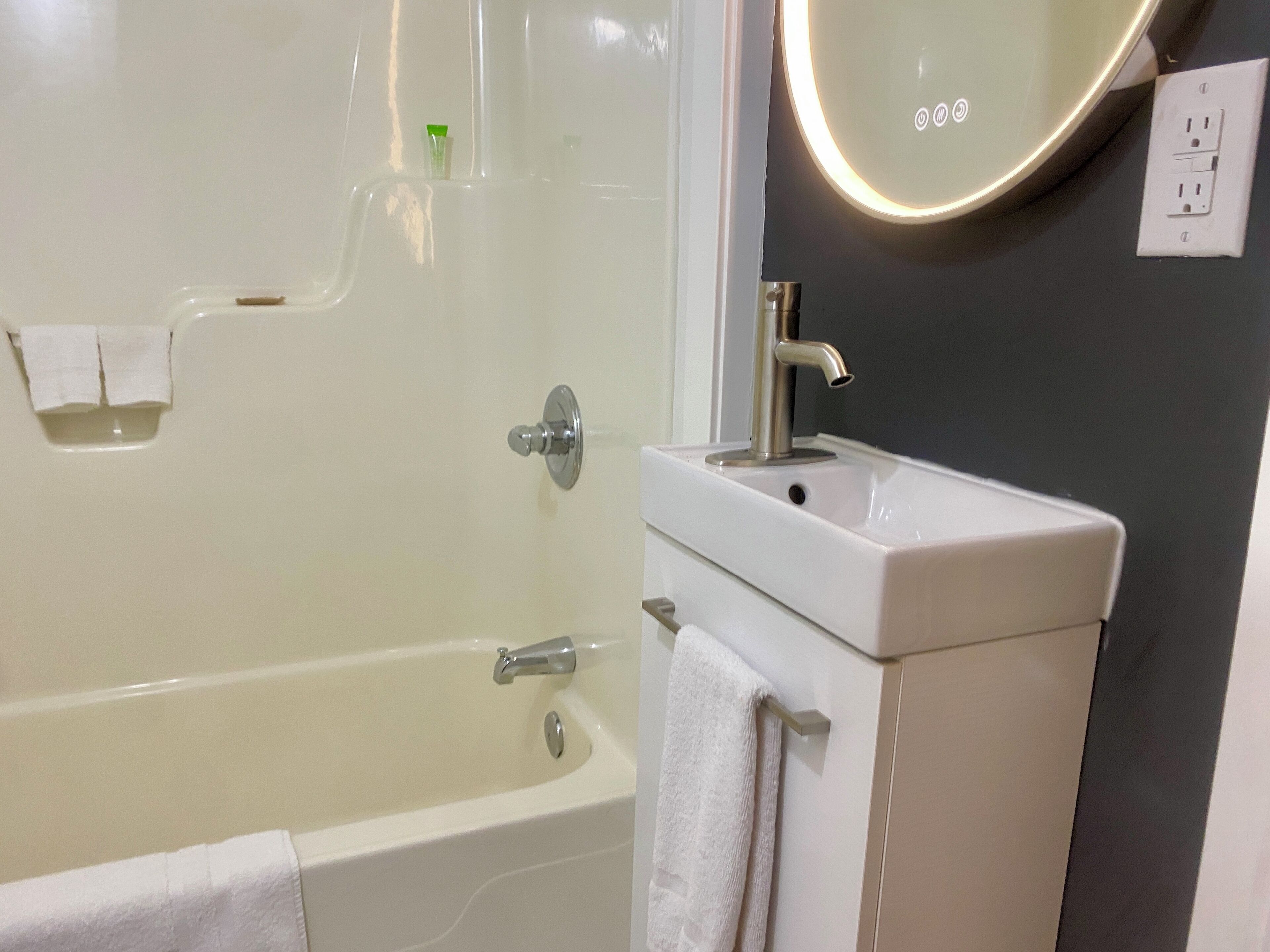 A bathroom with a bathtub, a sink, and a mirror.