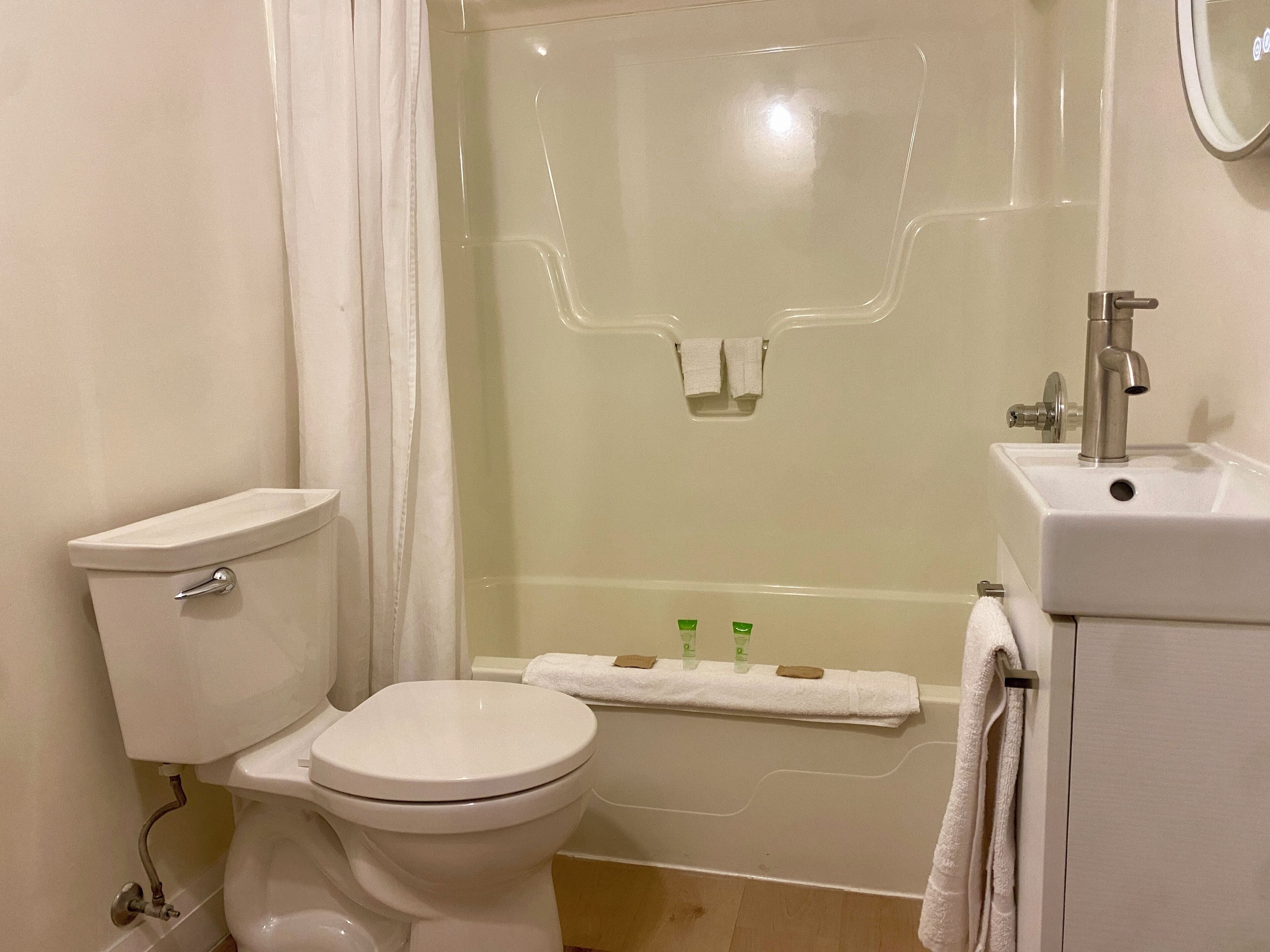 A bathroom with a toilet, shower, and sink.