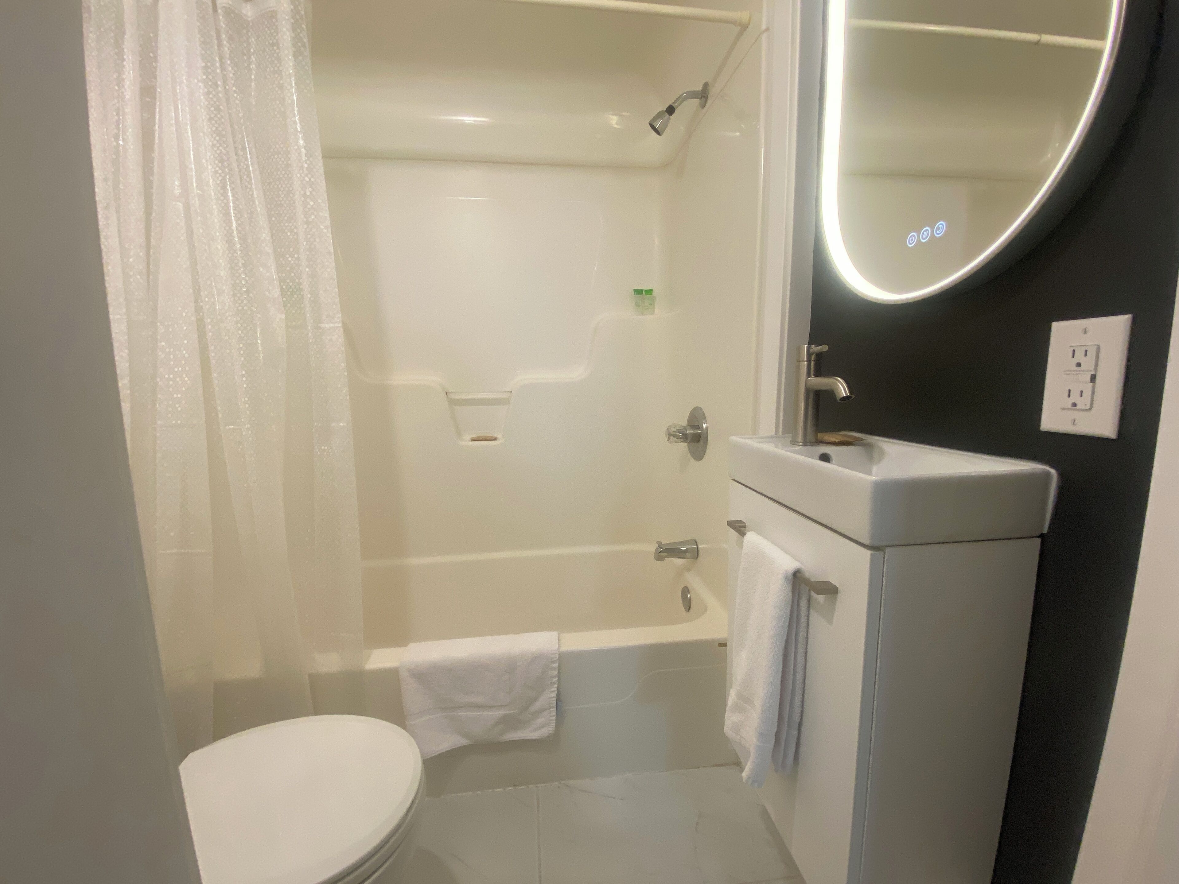 Un bagno con un water, una vasca, un lavandino e uno specchio.