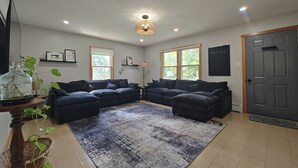 Sala de estar com sofá seccional, tapete grande e lustre.