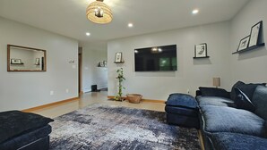 Sala de estar moderna com uma televisão grande, um candelabro e um sofá azul.