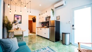 A modern kitchen with white cabinets, a stainless steel refrigerator, and a small dining area with a table and chairs.
