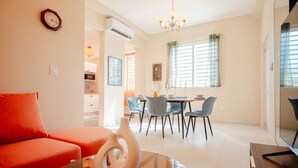 A modern living room with a red sofa, a dining area with a table and chairs, and a kitchen in the background. - Casa Lotus「UNIT 2「Tembleque」 (San Juan)