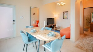 A modern living room with a dining area, featuring a round table with blue chairs, a television, and a sofa. - Casa Lotus「UNIT 2「Tembleque」 (San Juan)