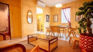 A living room with a glass coffee table, wooden chairs, a dining table, and a potted plant. - Casa Lotus「UNIT 4「Limber」 (San Juan)