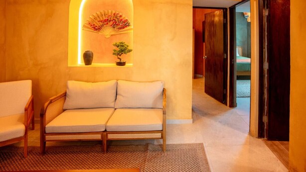 A cozy room with a sofa, a small table with a vase and a plant, and a decorative fan. - Casa Lotus「UNIT 4「Limber」 (San Juan)