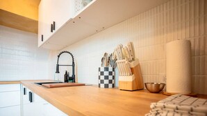 A modern kitchen with a wooden countertop, a black faucet, and a checkered knife holder. - Casa Lotus「UNIT 4「Limber」 (San Juan)