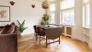 Un coin repas avec une table ronde, des chaises, un vase de fleurs et une suspension.