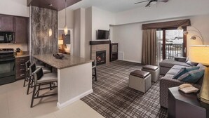 A modern living room with a fireplace, a bar area, and a seating area with a sofa and ottomans.