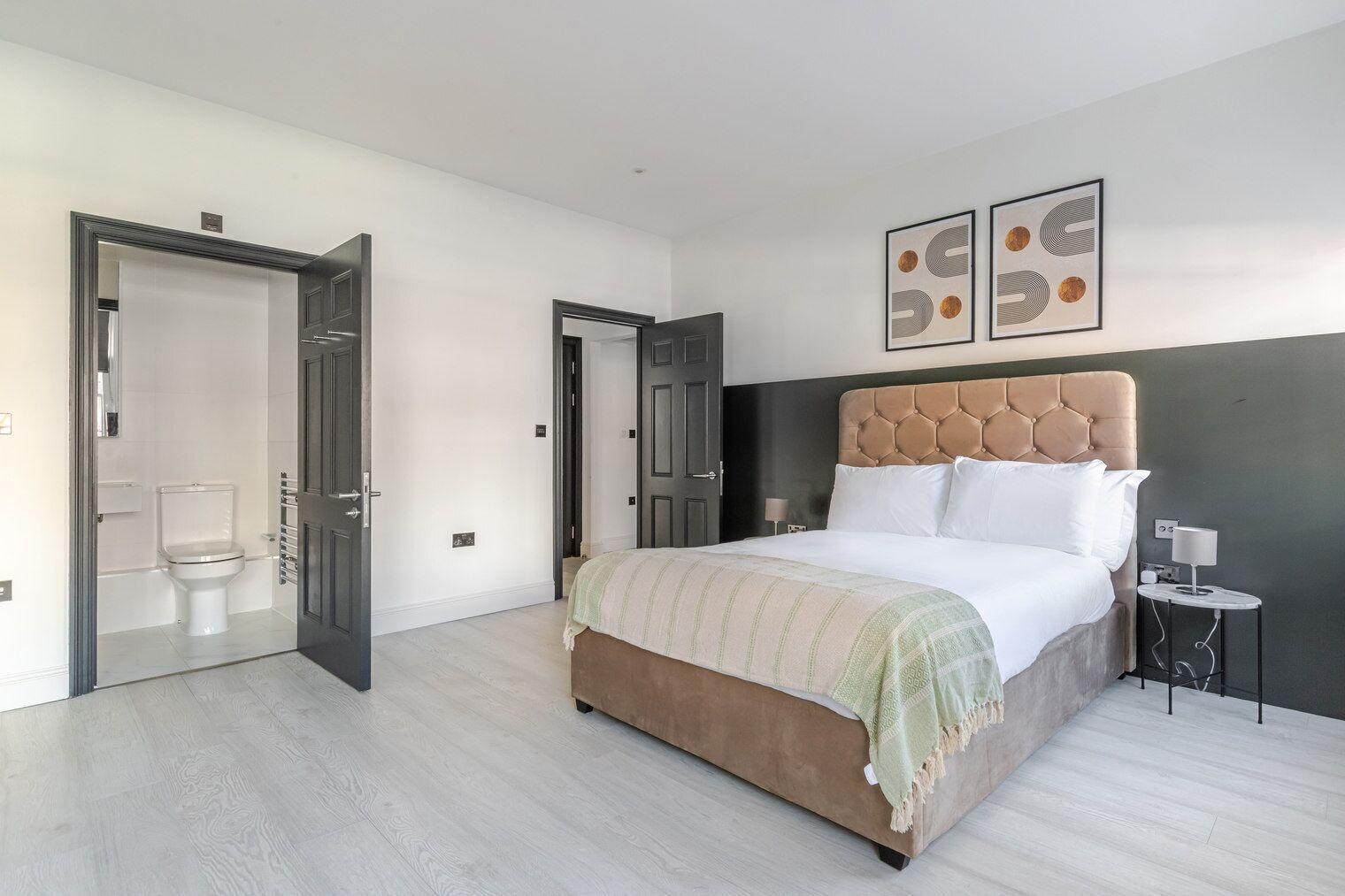 Une chambre moderne avec un grand lit, une table de chevet et une œuvre d’art accrochée au mur.