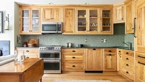 Une cuisine avec des meubles en bois, un four à micro-ondes, un four traditionnel et un dosseret carrelé.