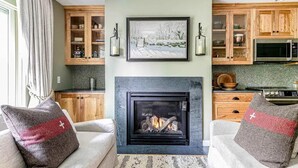 Un salon chaleureux avec une cheminée, des meubles en bois et un tableau encadré au-dessus.