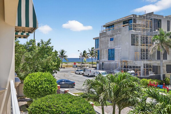 A modern building with a construction site, parked cars, and a view of the ocean.