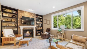 A cozy living room with a fireplace, a large bookshelf, a leather sofa, and a comfortable seating area.