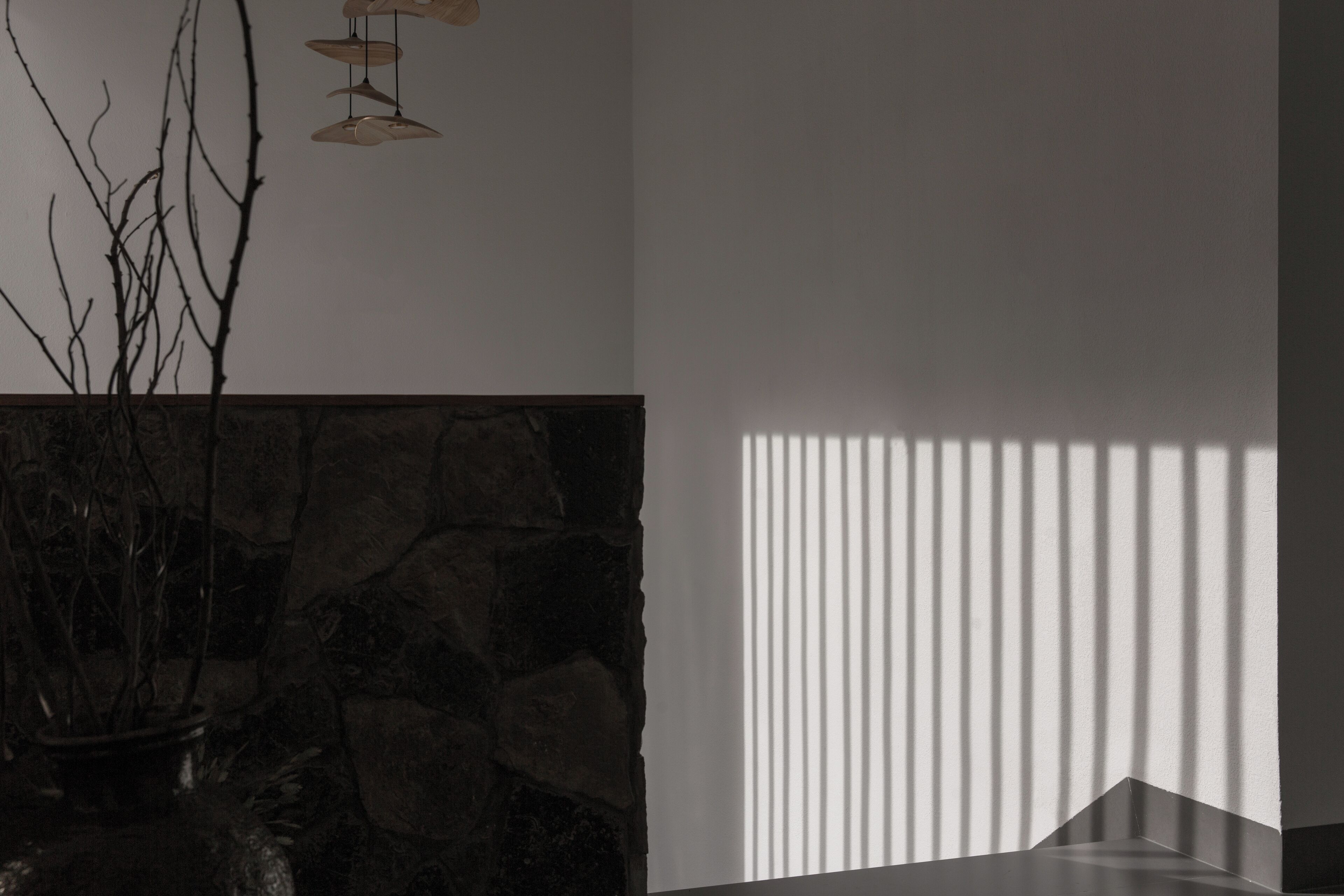A room with a stone wall, a potted plant, and a window with vertical blinds.