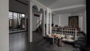 A spacious living area with a staircase, a sofa set, and a dining table. - SIXI Conglu Design Aesthetics Hotel (Lijiang)