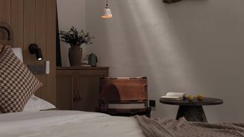 A bedroom with a bed, a wooden headboard, a bedside table with a lamp, and a small table with a book and lemons.