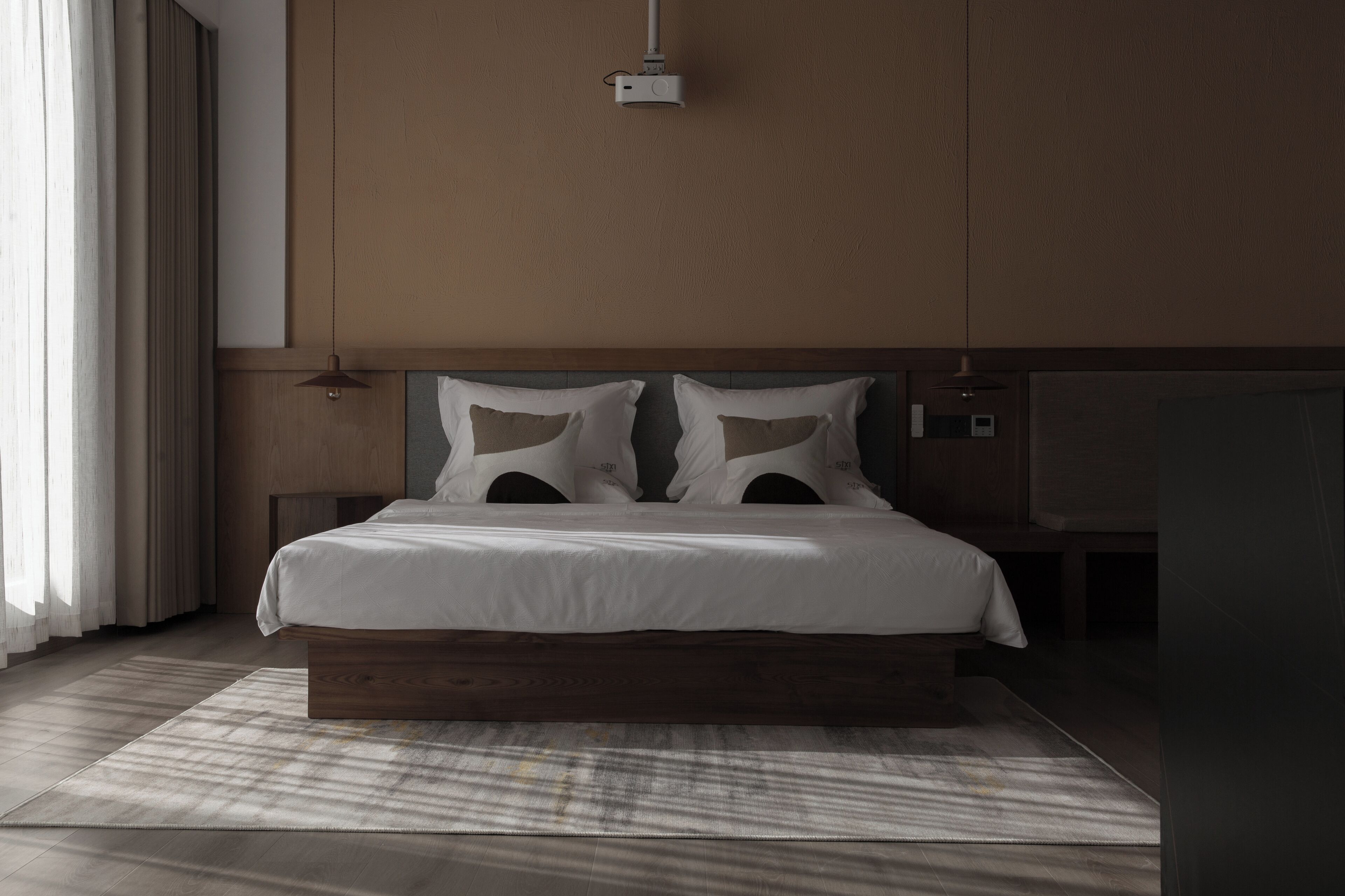 Ein modernes Schlafzimmer mit einem hölzernen Bettgestell, weißer Bettwäsche und einem großen Fenster mit Vorhängen.