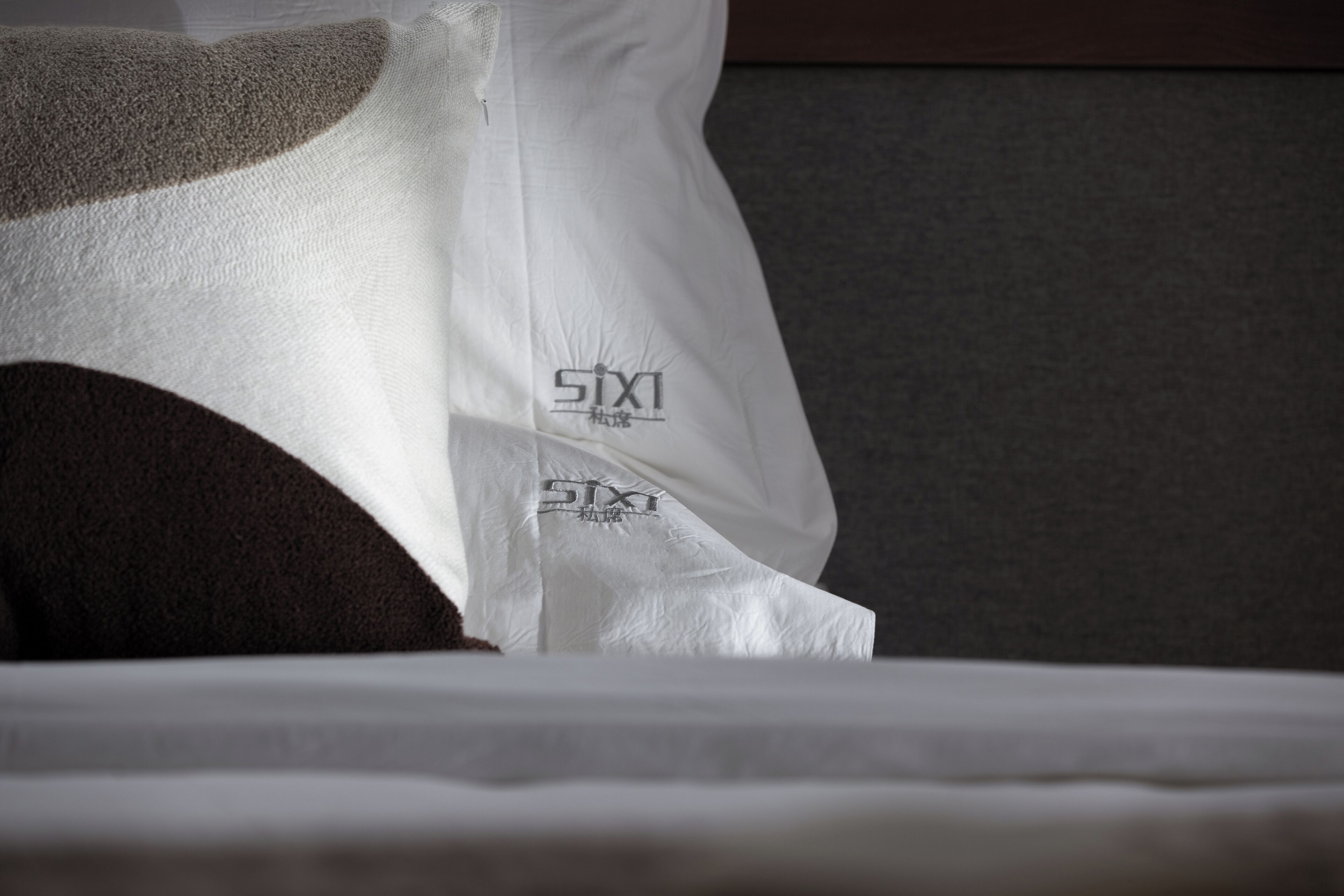 Een wit kussen met het logo “SIXI” op een bed.