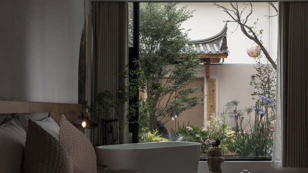 A bedroom with a large window, a bed with pillows, a bedside table, and a decorative vase. - SIXI Conglu Design Aesthetics Hotel (Lijiang)