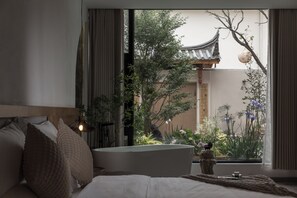 A bedroom with a large window, a bed with pillows, a bedside table, and a decorative vase. - SIXI Conglu Design Aesthetics Hotel (Lijiang)