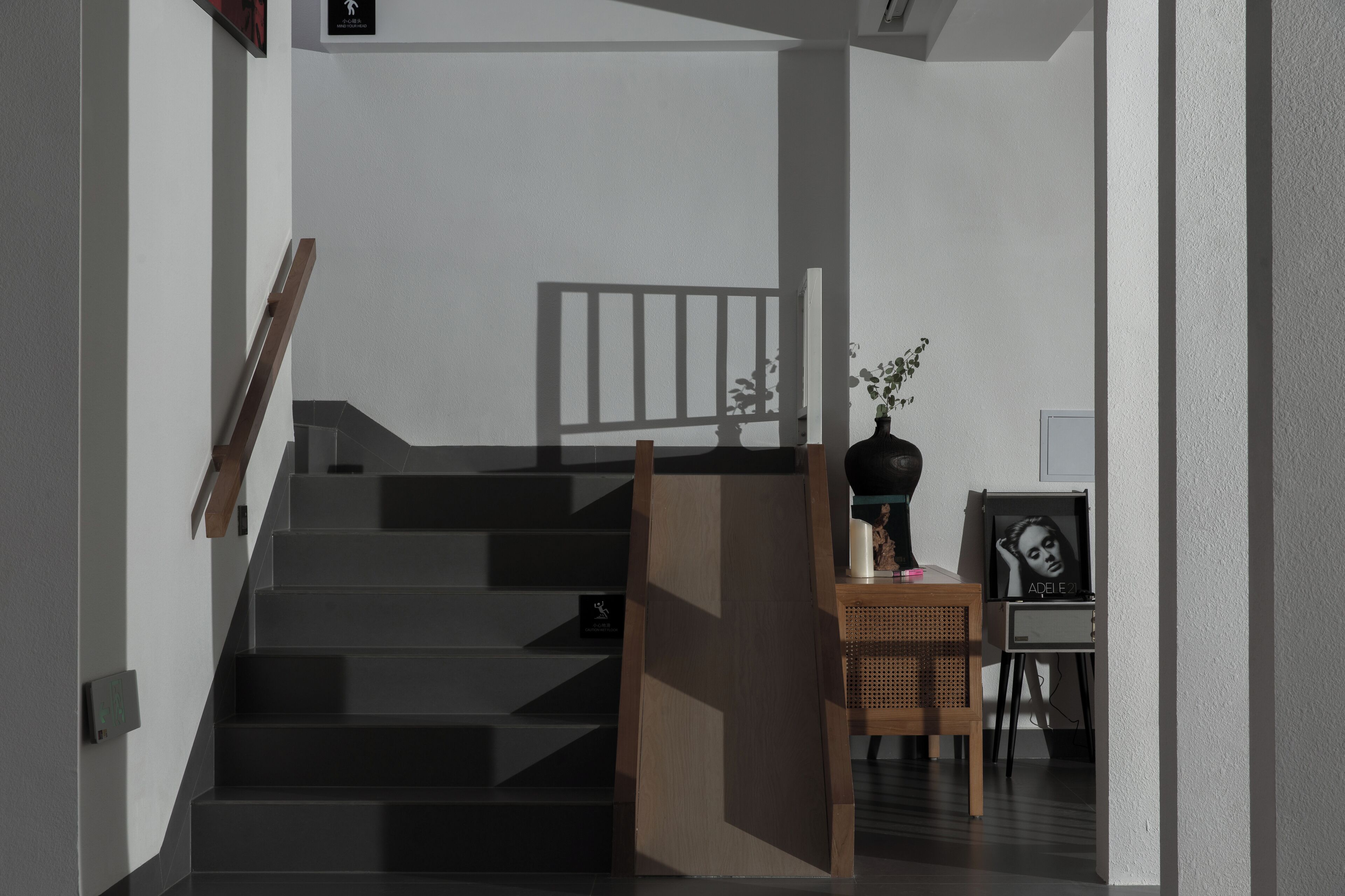 Un escalier moderne avec une rampe en bois et un luminaire fixé au mur.