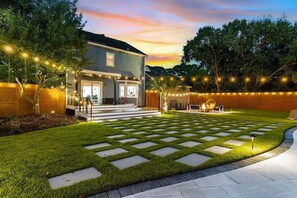 A residential backyard with a house, a paved patio, and string lights. - OG Paradise | Private Pool & Hot Tub | Luxe Oasis (Wilmington)