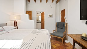 Een slaapkamer met een bed, een stoel, een tafel en een televisie.