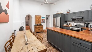 Een moderne keuken met een groot eiland, donkergrijze kastjes en een houten eettafel.
