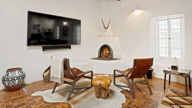 Een moderne woonkamer met een open haard, lederen fauteuils, een televisie en een ruig tapijt.