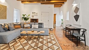 Een moderne woonkamer met een hoekbank, een salontafel en een eethoek met een houten tafel en stoelen.