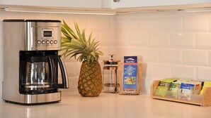 Eine Küche mit Kaffeemaschine, einer Ananas, einem Glasbehälter und einem Kaffeebohnenspender.