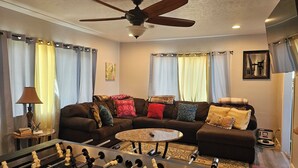 A living room with a sofa, coffee table, and foosball table. - 3-bedroom house in awesome Billings with AC, fitness room (Billings)
