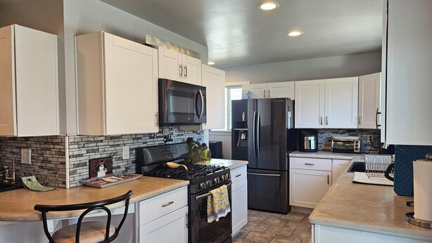 A modern kitchen with white cabinets, a black refrigerator, a microwave, and a stove. - 3-bedroom house in awesome Billings with AC, fitness room (Billings)