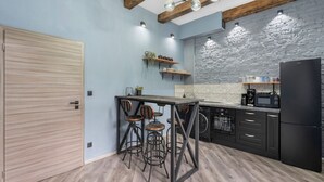 A modern kitchen with a bar area, exposed wooden beams, and a stone accent wall. - Carlsbad Suites by Interhome (Carlsbad)