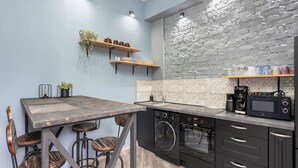 A modern kitchen with a wooden table, bar stools, a built-in oven, and a coffee machine. - Carlsbad Suites by Interhome (Carlsbad)