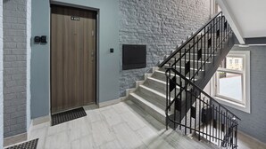 A modern interior with a wooden door marked '425', a stone wall, and a staircase with black railings. - Carlsbad Suites by Interhome (Carlsbad)