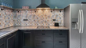 A kitchen with a tiled backsplash, a stainless steel refrigerator, and a black range hood. - Carlsbad Suites by Interhome (Carlsbad)