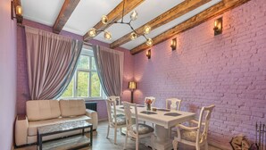 A cozy room with a wooden ceiling, a dining table with chairs, a sofa, and a window with curtains. - Carlsbad Suites by Interhome (Carlsbad)