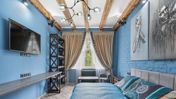 A modern bedroom with a bed, a TV, a bookshelf, and a window with curtains. - Carlsbad Suites by Interhome (Carlsbad)