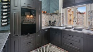A modern kitchen with dark cabinetry, a built-in oven, and a wine rack. - Carlsbad Suites by Interhome (Carlsbad)