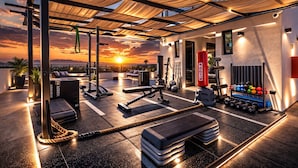 A rooftop gym with exercise equipment, a punching bag, and a view of the sunset. - Luxury Cabo Studio | Rooftop Pool, Hot Tub & Walk to Beach (Cabo San Lucas)