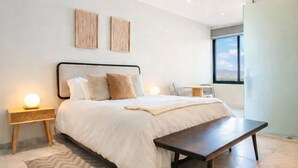 A modern bedroom with a large bed, bedside tables, a bench, and a view of the outdoors. - Luxury Combo Suite | Rooftop Pool & Walk to Beach (Cabo San Lucas)